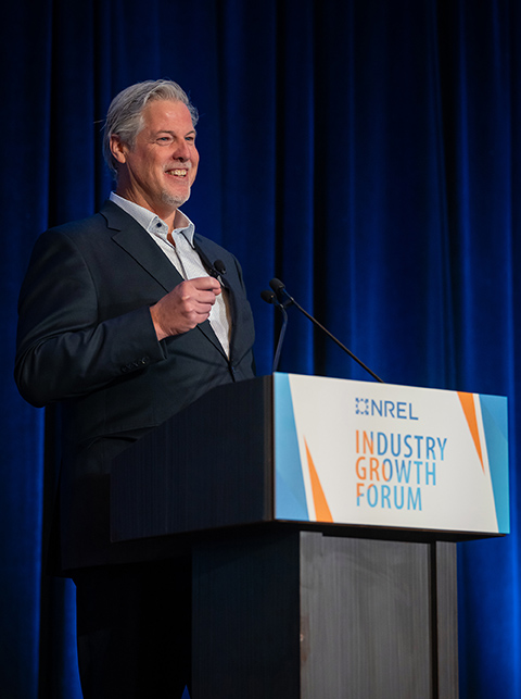 A man stands behind a podium labeled with Industry Growth Forum.
