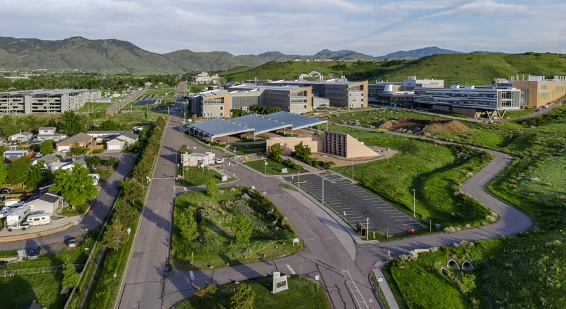 Aerial view of various modular buildings, including some with solar panels, with the mountains in the backdrop.