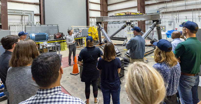 A tour group gathers around a person pointing out objects within a laboratory.