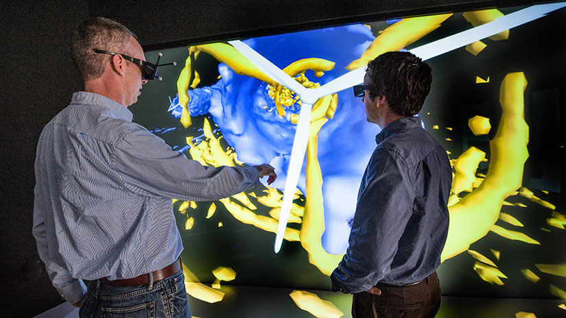 Two people wearing VR headsets looking at wind turbine on screen