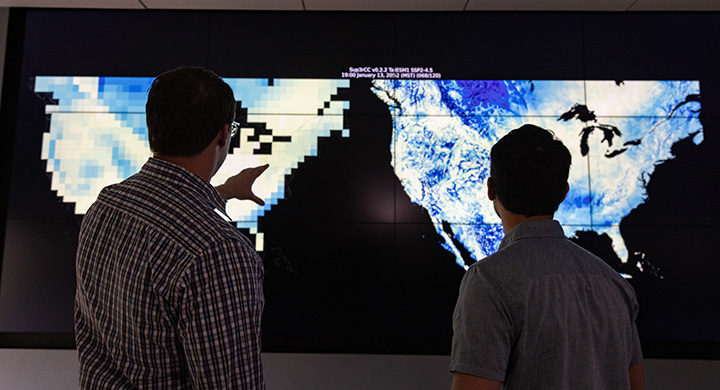 Two men looking at a large screen displaying typography of the United States.