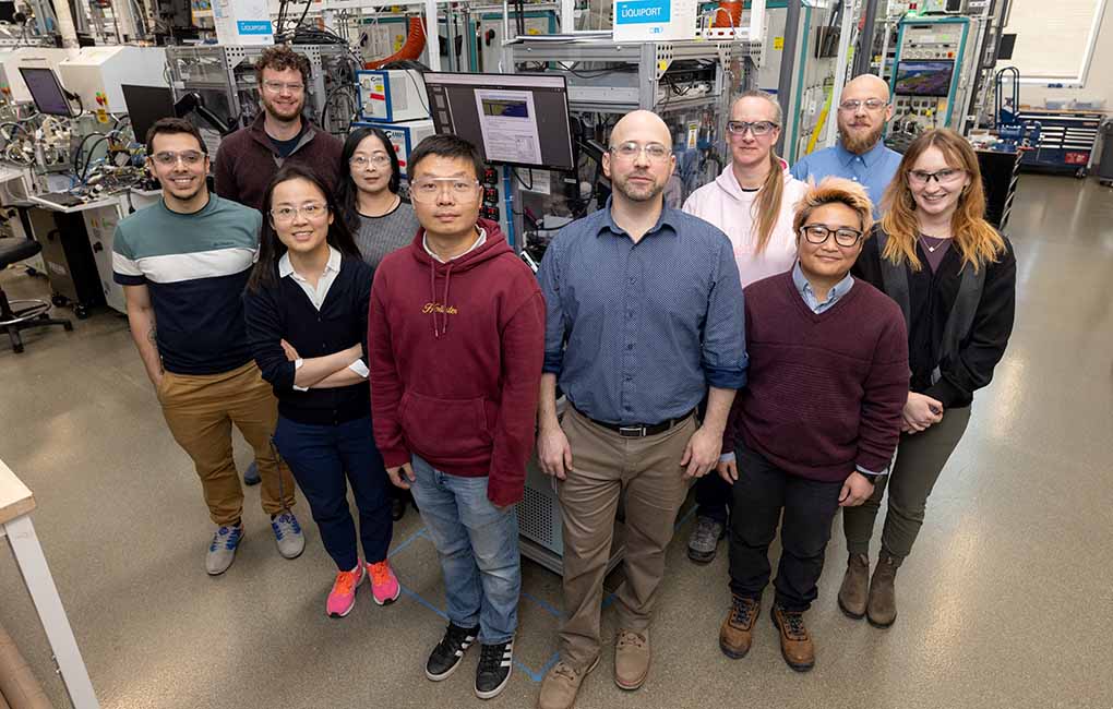 Ten people wearing safety goggles in a lab