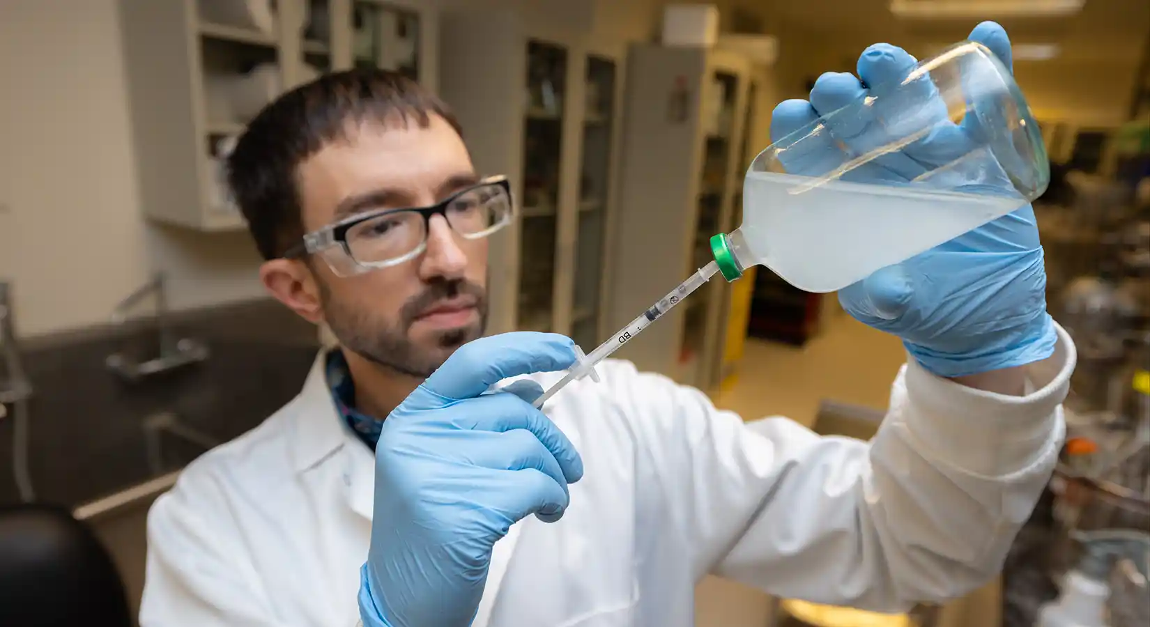 Biological science research technologist holds a sample from a bioreactor.