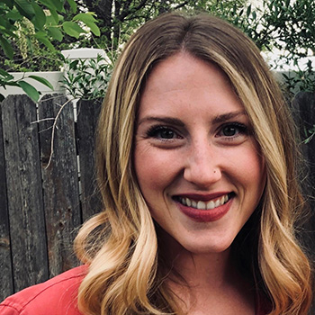 Photo of a woman standing in the mountains with a lake in background
