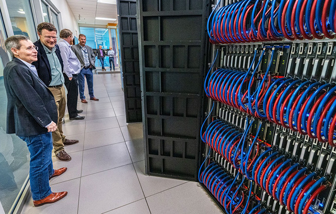 Researchers stand and look at wiring.