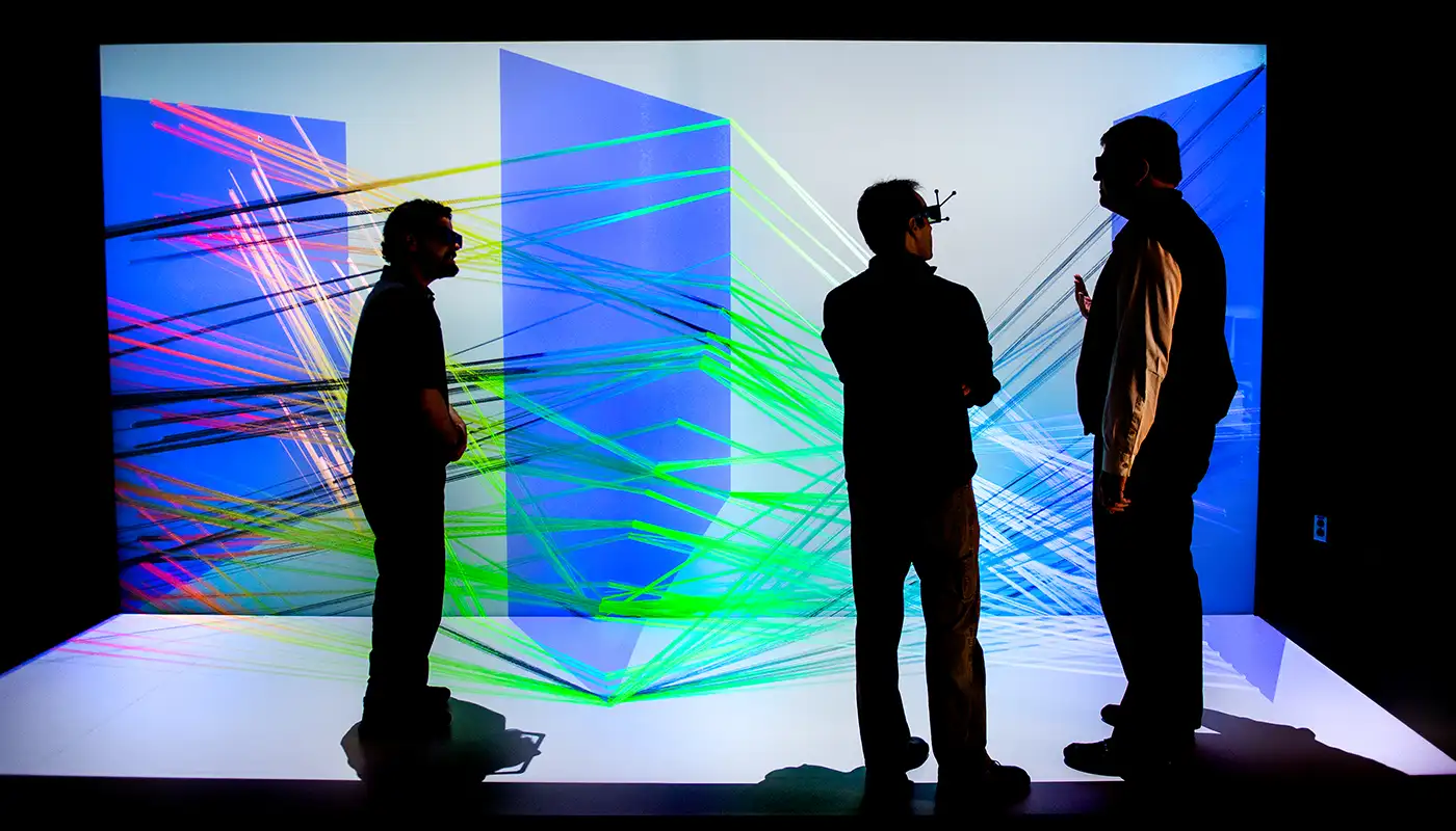 Photo of three people viewing a large-scale 3D visualization