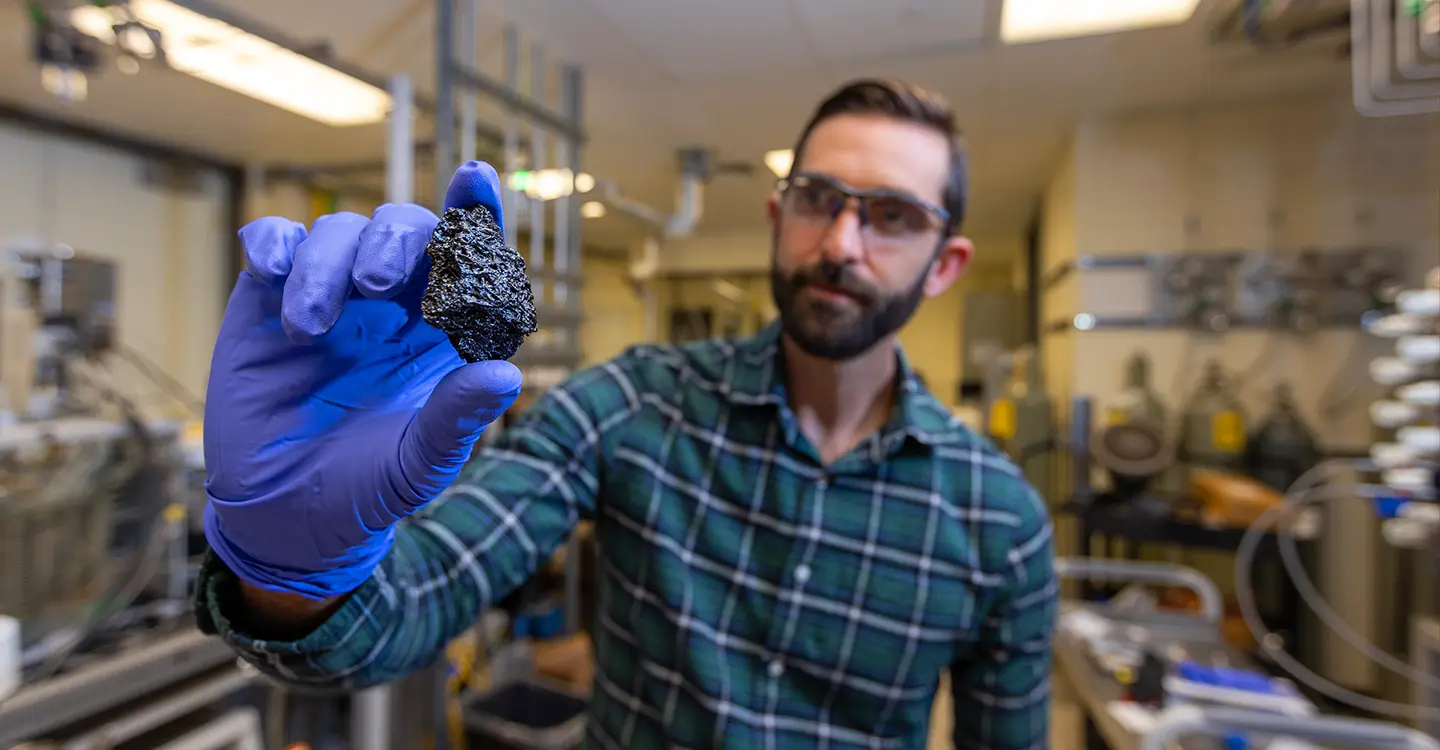 A researcher holds a chunk of bio-coke.