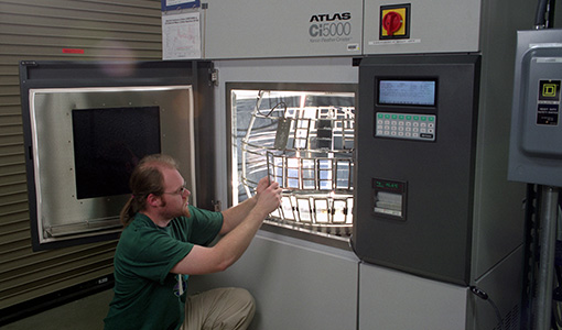 009935-flt Technician loading samples into an Atlas Ci5000 xenon arc weathering/lightfastness test chamber.