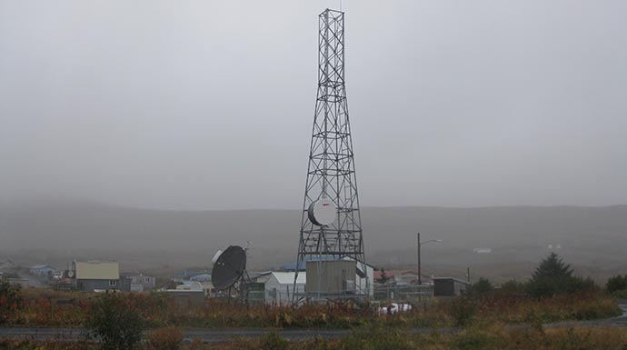 Radio tower stands in field during foggy day