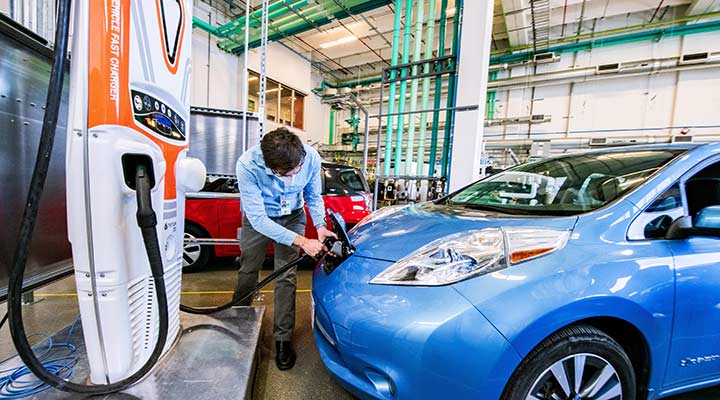 Photo of a researcher plugging in an electric vehicle in a laboratory in the ESIF.