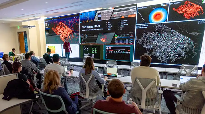 Large presentation screen with graphic and a seated audience.