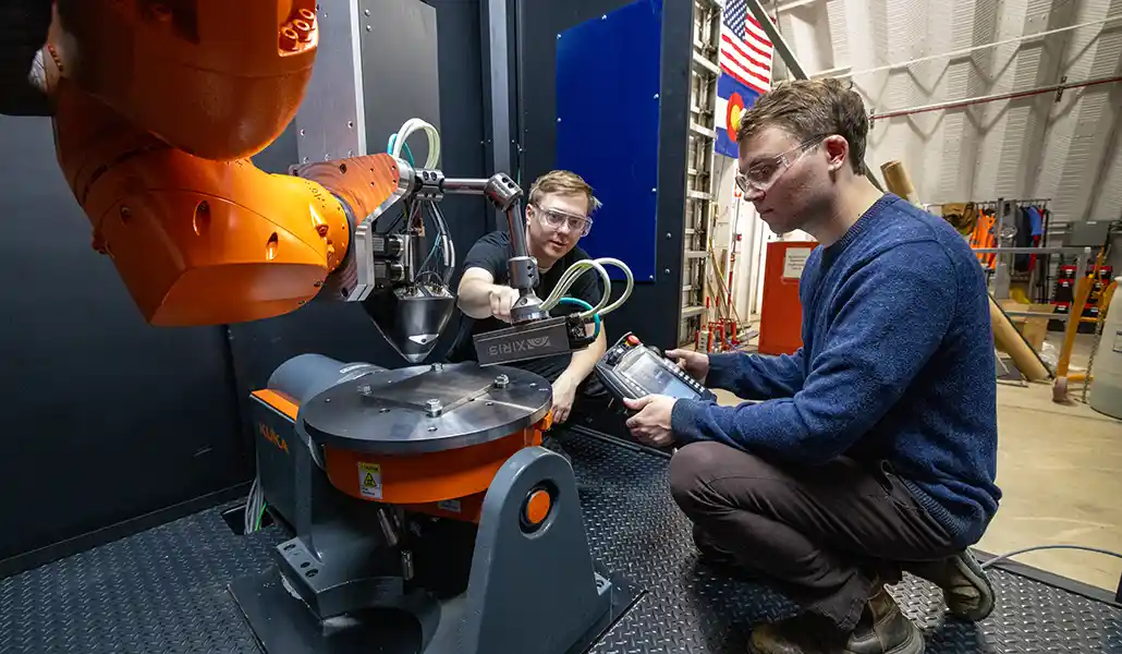 Staff receive training on a newly installed robotic laser metal deposition 3D printing system.