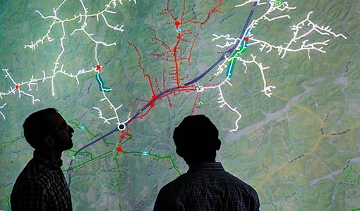 Photo of two researchers looking at a screen showing a distribution grid map