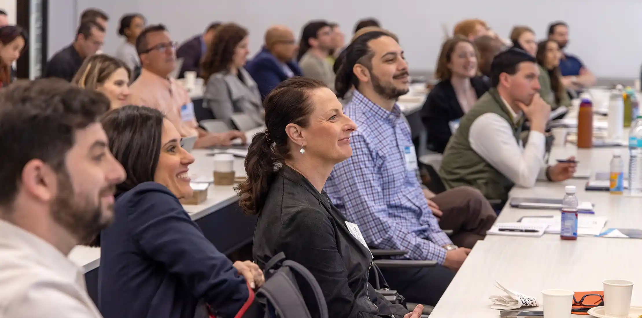 Conference attendees smile as they listen to presenters.