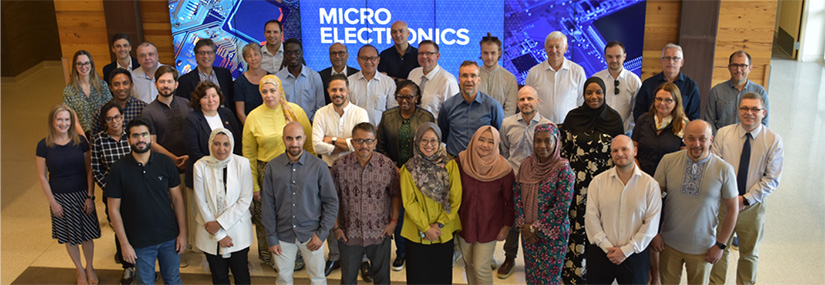 Photo of a group of people standing in front of a background that says Micro Electronics.
