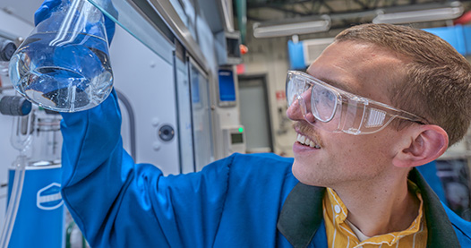 Researcher holds up a beaker to examine inside a lab.