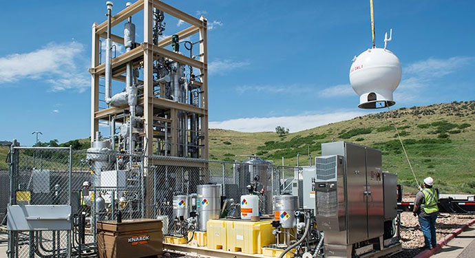 Crews crane a natural gas storage vessel into place in a bioreactor.