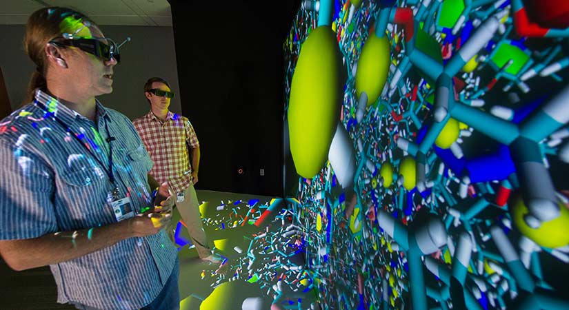 A photo of two researchers examining a colorful 3-D molecular model.