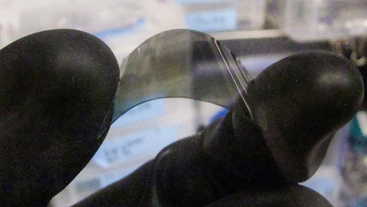 Photo of an index finger and a thumb holding a small, opaque square of film.