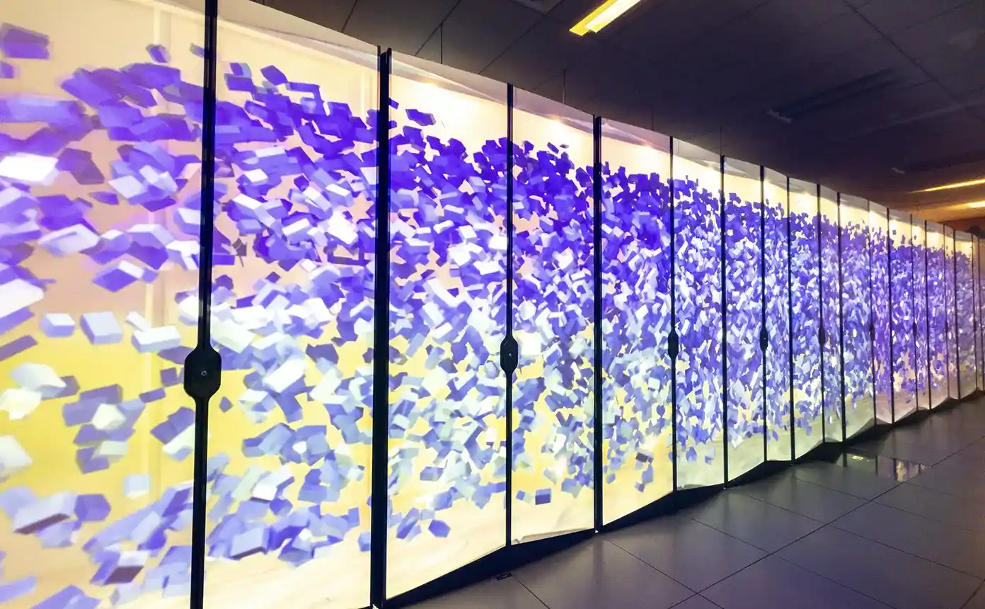 A row of high-performance-computing racks with LED-screen doors displaying colorful geometric imagery.