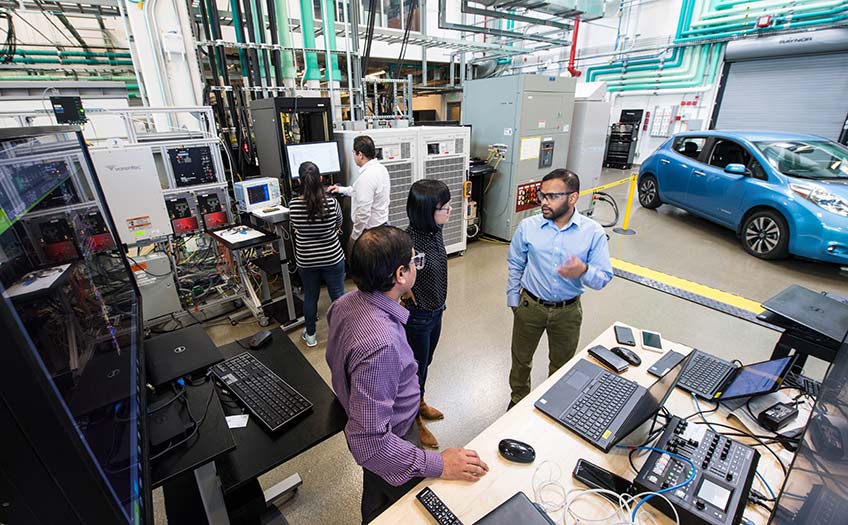 Researchers in a lab with a car in the background