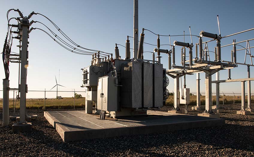 A power transformer nearby a wind turbine.