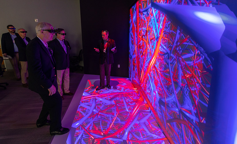 A group of people interact with a 3D data visualization system