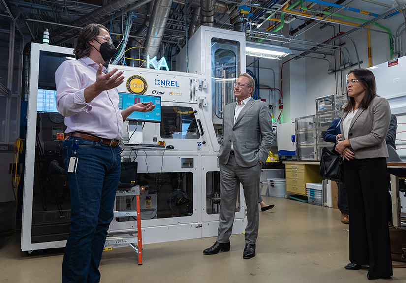 Three people speak in an NREL lab.