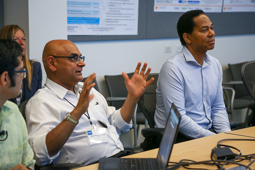 Photo of people seated at a table with one man speaking