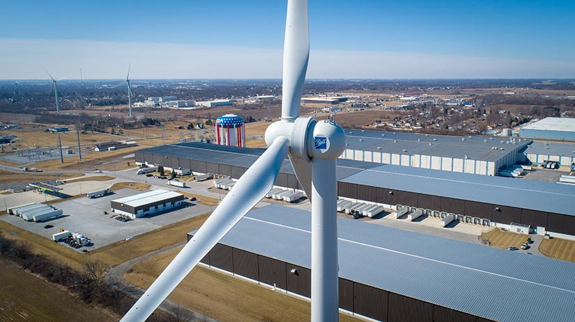 Wind turbine in the foreground with a small town in the background.