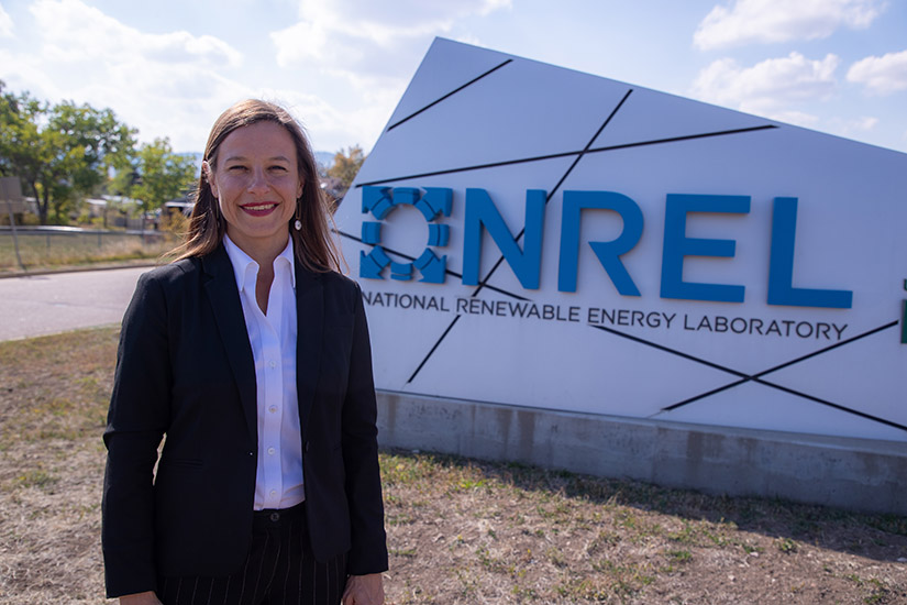 A woman stands in front of the NREL sign.