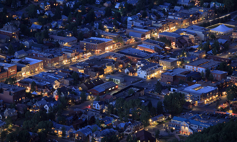 An aerial view of a neighborhood using electricity at night.