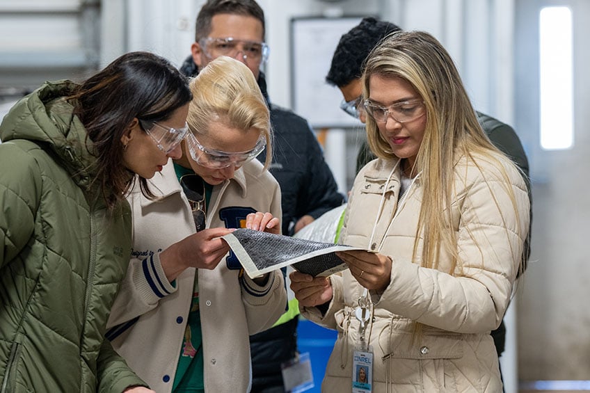 A group of people examining a sample of fabric material.
