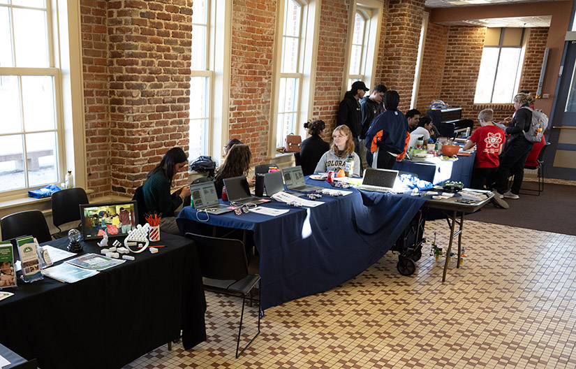 Students standing and sitting around two tables. 