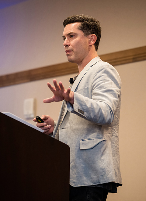 A man stands behind a podium talking.