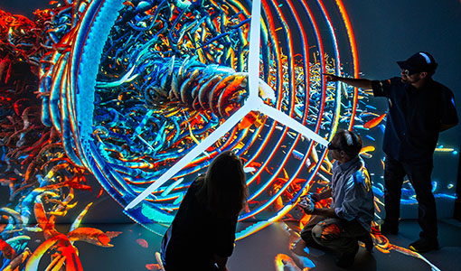 Continue reading about three researchers in silhouette interacting with a multicolor 3D visualization featuring a wind turbine.