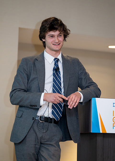 A man smiles while leaning on a podium.
