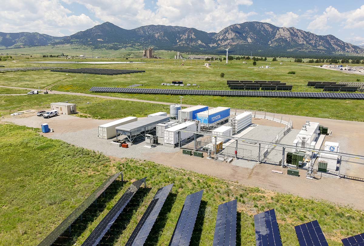 Aerial view of a research campus showing solar panel arrays and other facilities with mountains in the background