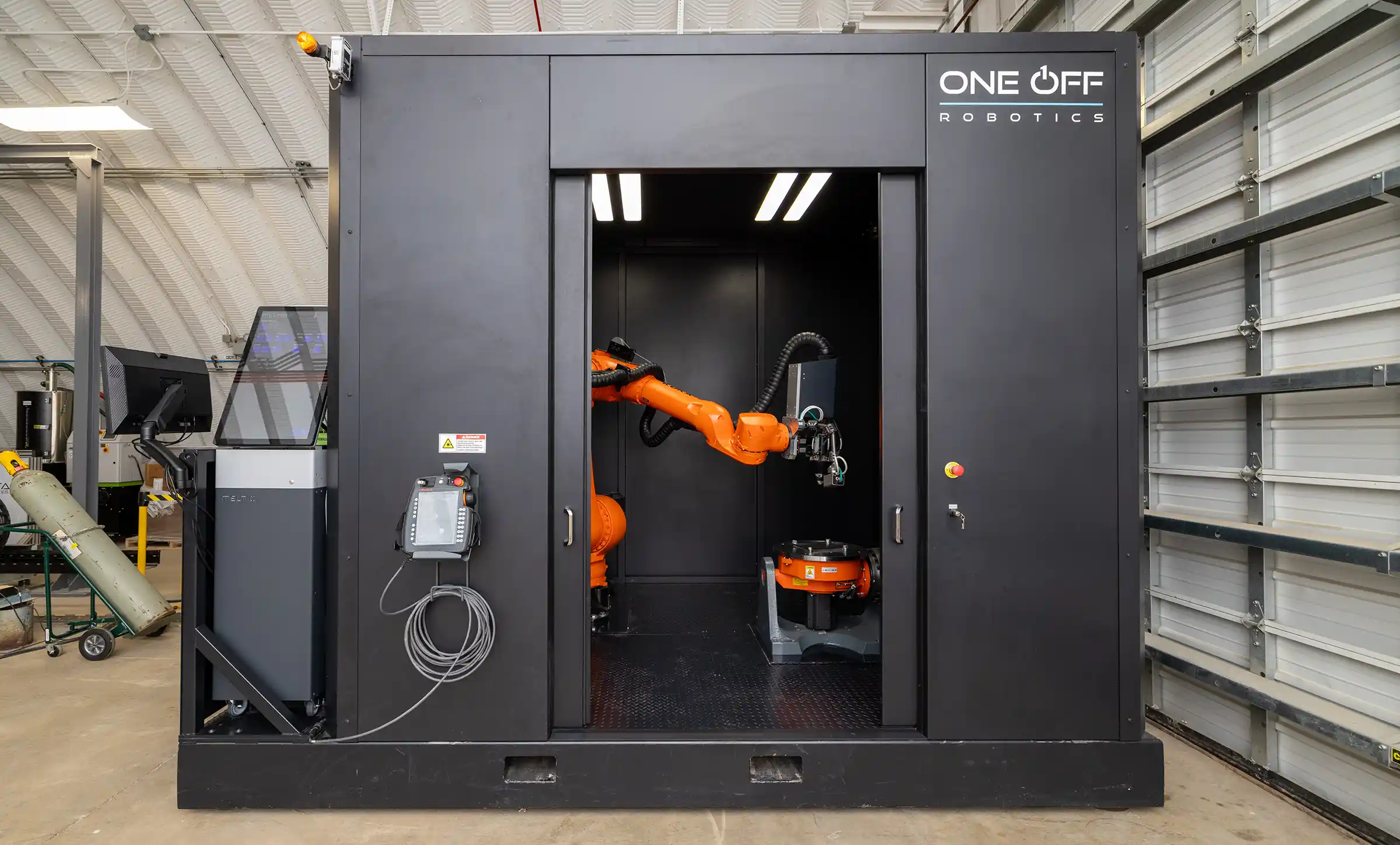A robotic arm housed inside a metal room the size of a large closet.