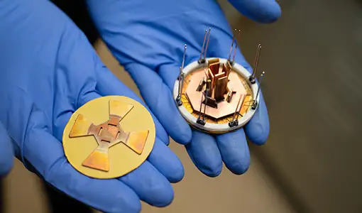 Continue reading about Two gloved hands hold a small octagonal power module and a corresponding attachment layer.