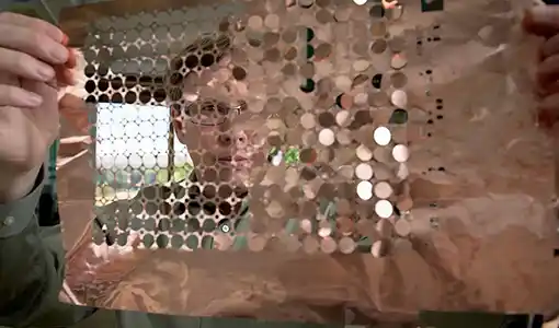 Continue reading about A person holds up a sheet of copper discs.