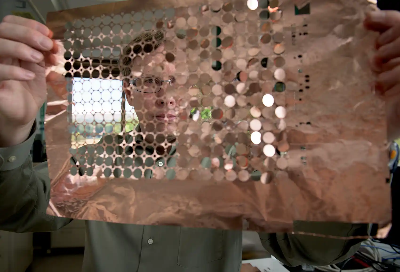 20260513-nlr-battery-innovation-awarded-nasa-invention-of-the-year-034831 A person holds up a sheet of copper discs.