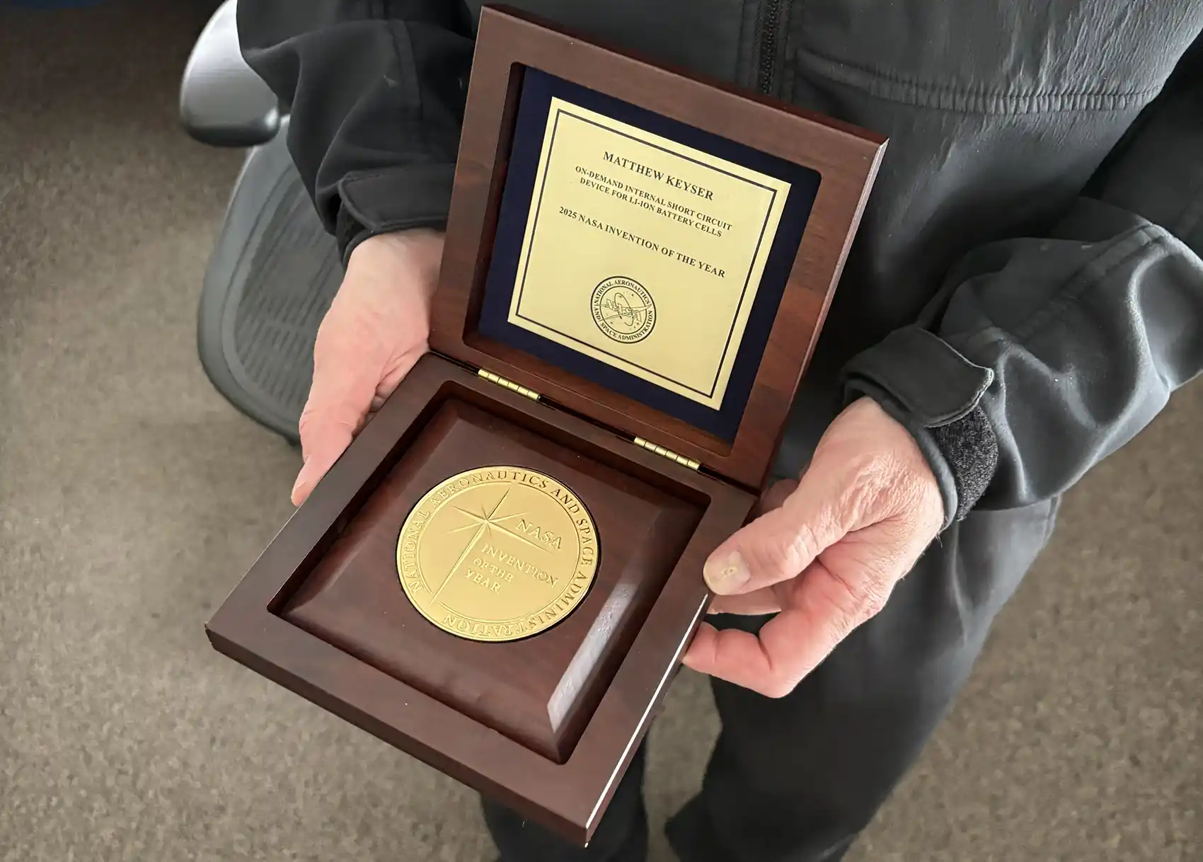 20260513-nlr-battery-innovation-awarded-nasa-invention-of-the-year-award A pair of hands holding a wood box with an award inside.