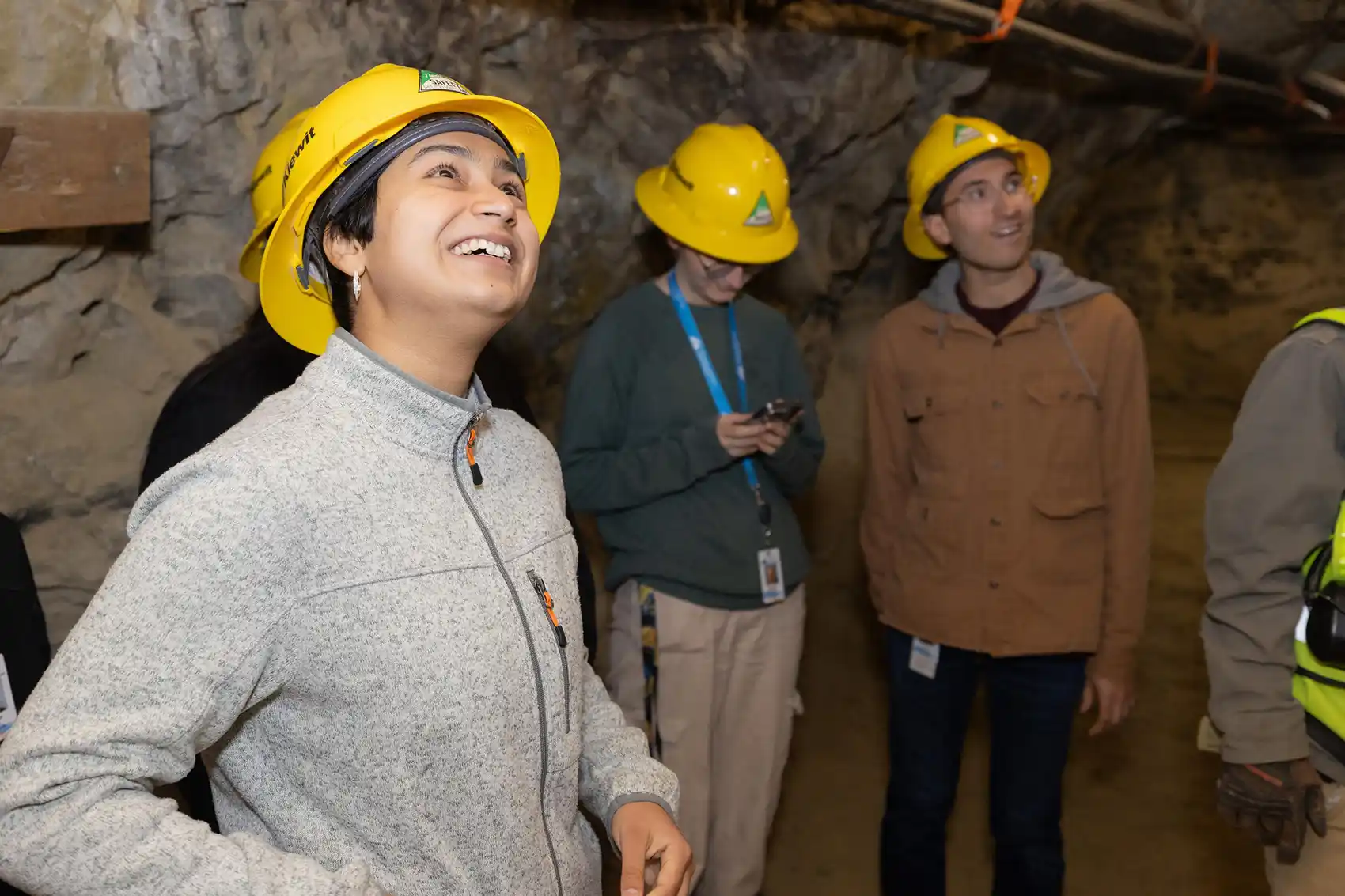 Three people in hard hats looking around a mine shaft.