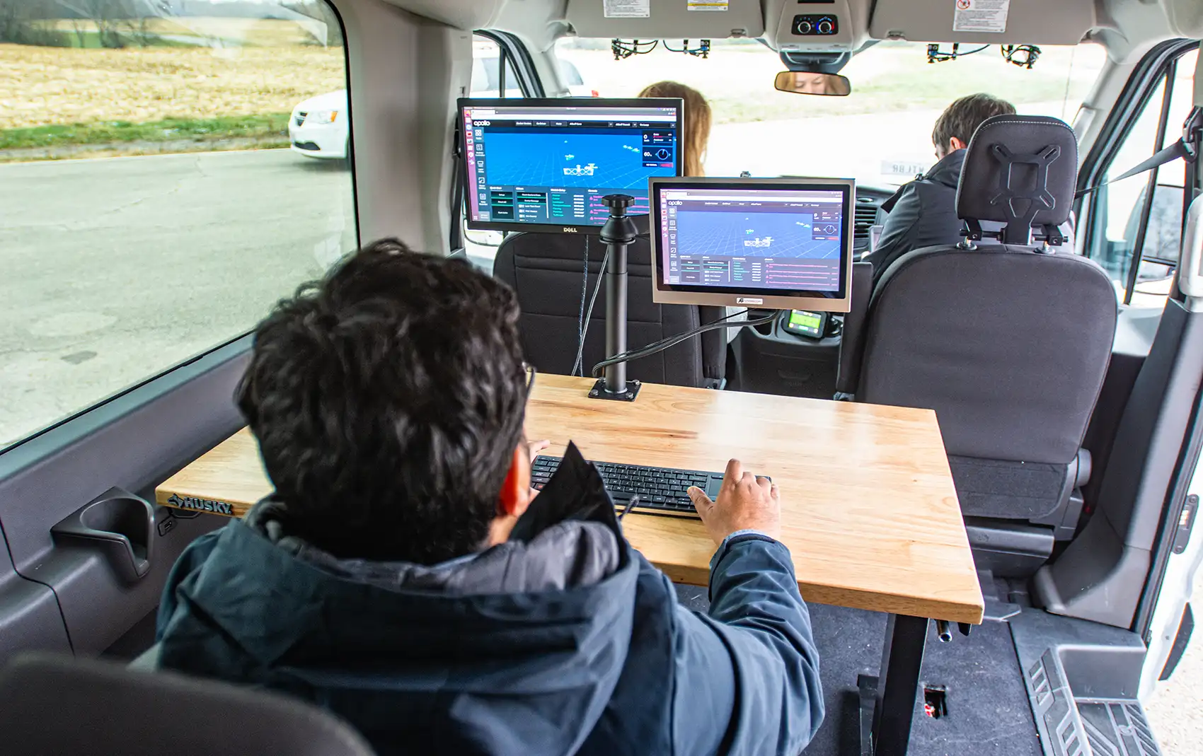 An engineer in the back of a truck monitors a connected truck’s progress on several computer screens.