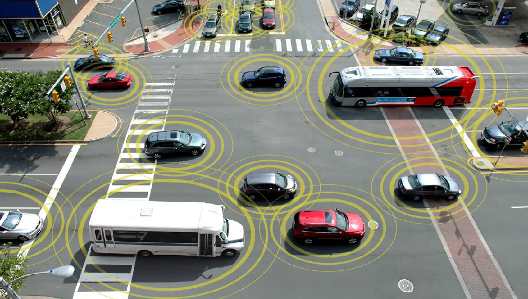 Vehicles surrounded by digitally generated rings cross a busy intersection, signifying that they are visible to smart traffic infrastructure.