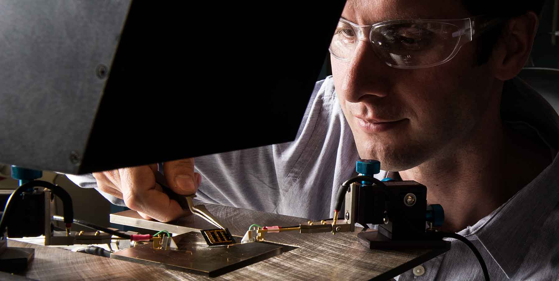 Photo shows a researcher positioning a solar cell he developed on a solar simulator.