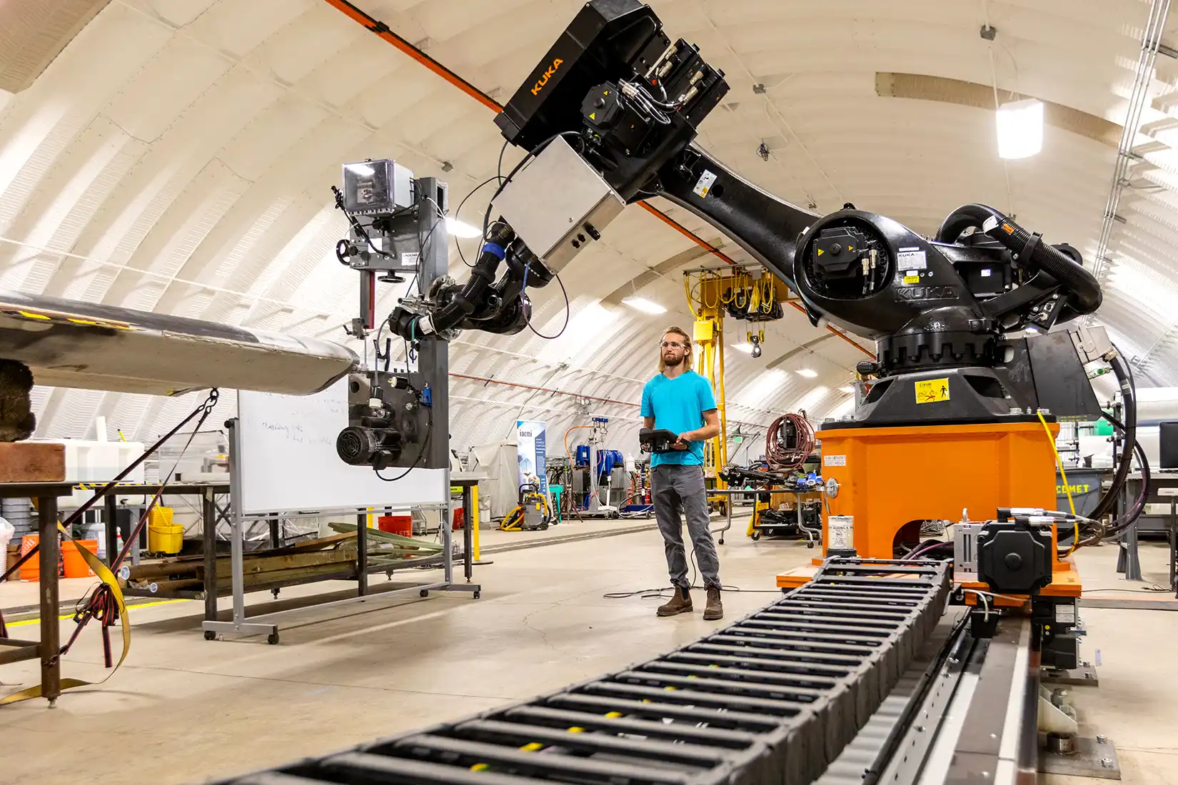 An intern stands under a large robotic arm.