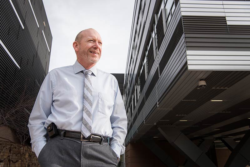 A man stands outside on the grounds of the NREL campus.