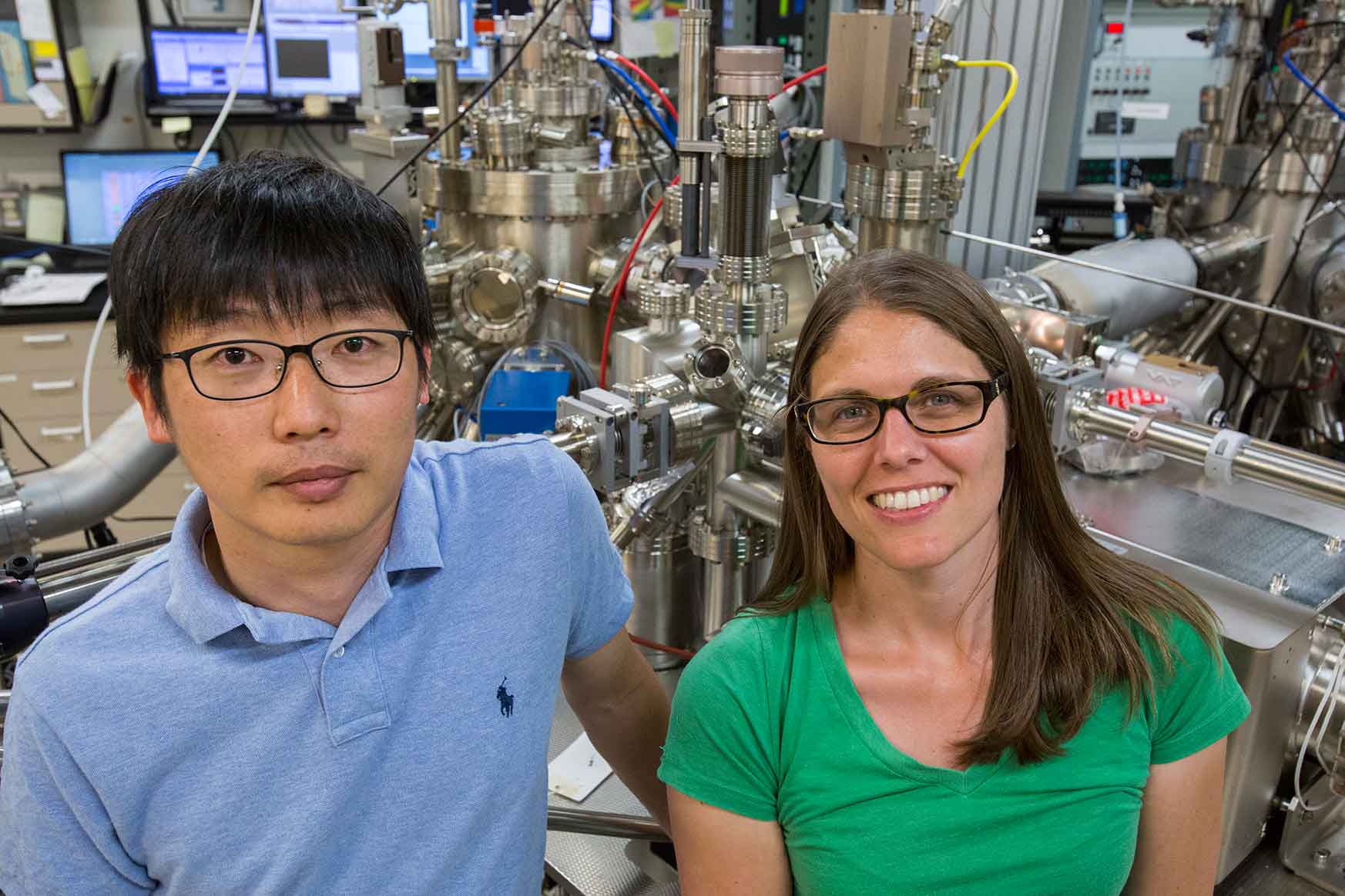 A man and a woman stand in front of laboratory equipment at NREL.